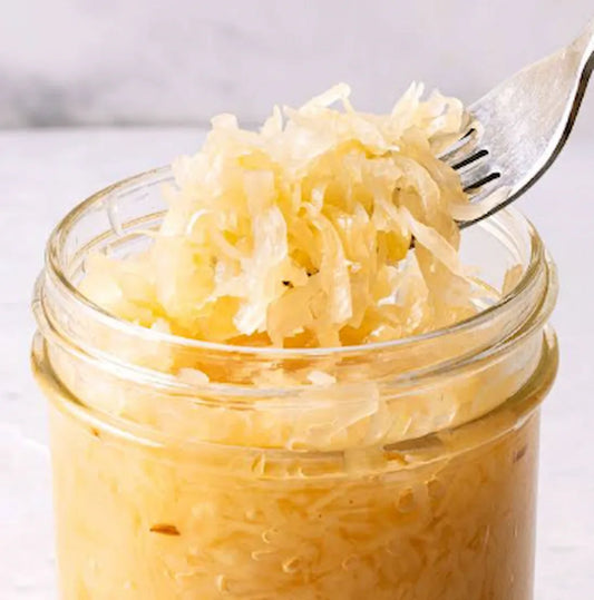 A fork lifting raw sauerkraut from a glass jar — unpasteurised, live-culture sauerkraut made in South Africa