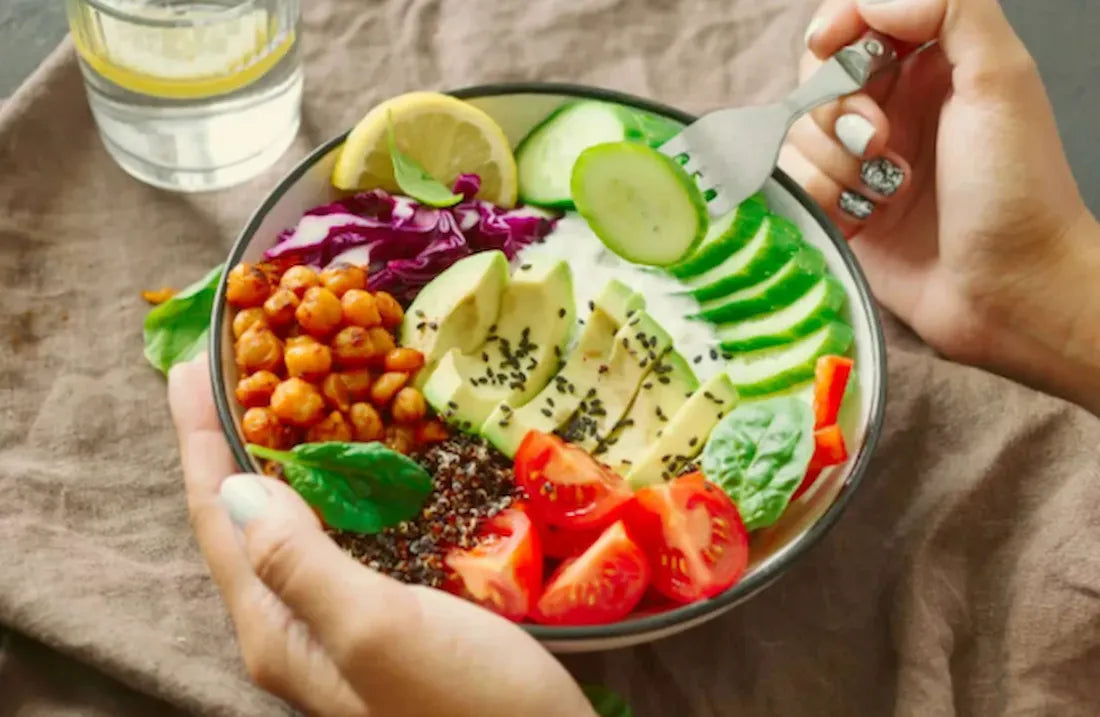 A colourful salad bowl with avocado, cucumber, tomato, chickpeas, red cabbage and leafy greens.