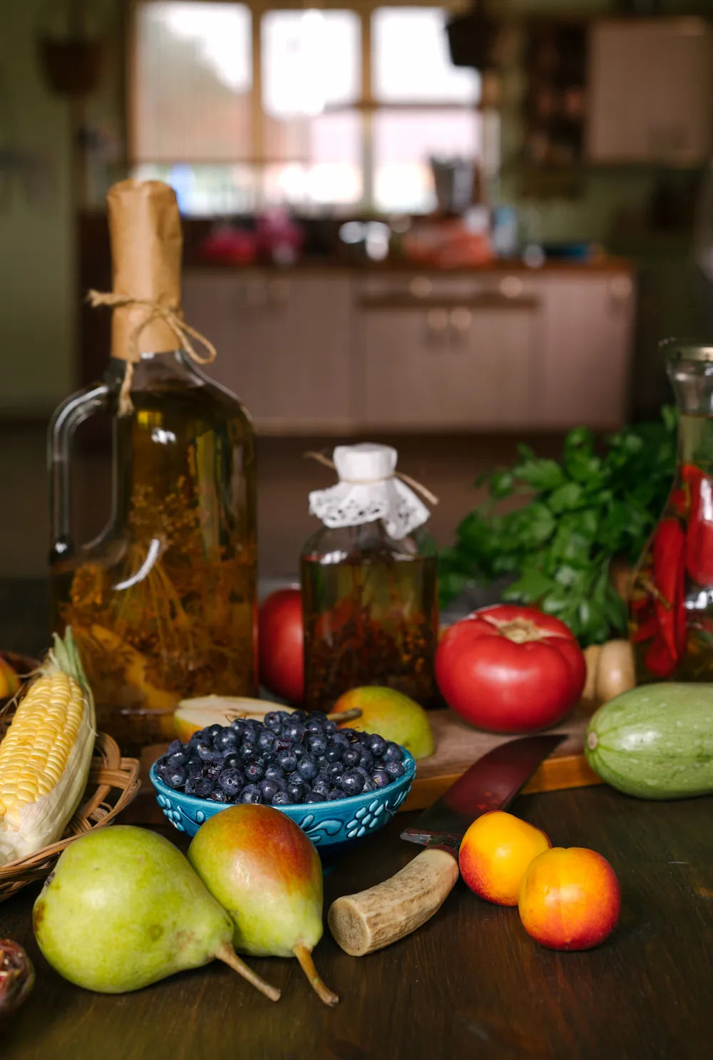 Fresh fruits, vegetables and fermented bottles on a kitchen table — ingredients for a healthy gut microbiome